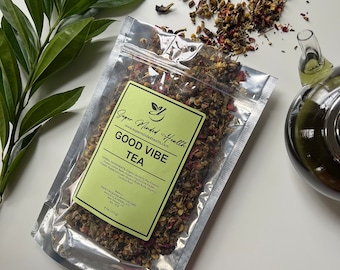 May include: A silver pouch filled with a blend of dried herbs and flowers labelled "Good Vibe Tea" by "Super Minded Health". The pouch is on a white surface with loose tea scattered around it.
