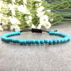 May include: A turquoise beaded bracelet with a black adjustable cord.
