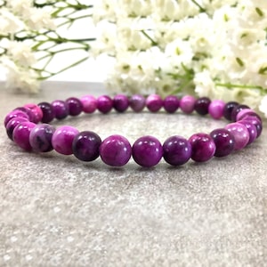 May include: A purple and pink gemstone bracelet with round beads. The bracelet is made of natural stones and is a beautiful and unique piece of jewelry.