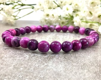 May include: A purple and pink gemstone bracelet with round beads. The bracelet is made of natural stones and is a beautiful and unique piece of jewelry.