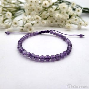 May include: A purple amethyst beaded bracelet with a knotted cord closure.