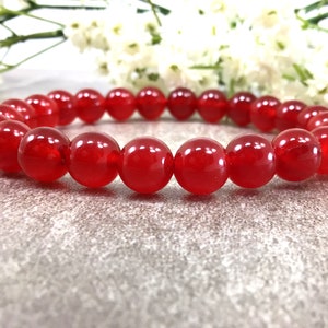 May include: A red gemstone bracelet with round beads.