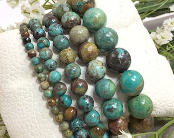 May include: A strand of turquoise beads with brown and green marbling. The beads are round and have a smooth, polished finish.