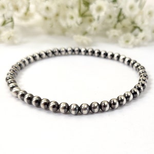 May include: A silver beaded bracelet with a simple design. The beads are small and round, and the bracelet is made of a single strand.