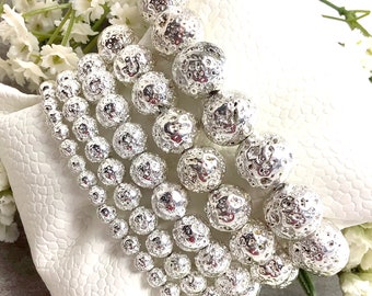 May include: A set of five silver lava rock bead bracelets. The beads are round and have a textured surface. The bracelets are stacked on top of each other.