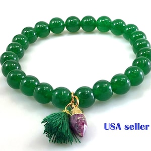 May include: A green jade beaded bracelet with a gold charm featuring a pink gemstone and a green tassel. USA seller.