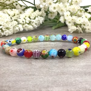 May include: A colorful beaded bracelet featuring a variety of glass beads in different colors and patterns. The beads are strung together to form a circular shape. The bracelet is a vibrant accessory.