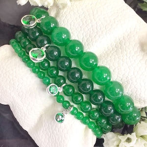 May include: Four green jade stone bracelets with silver charms and green crystal accents.