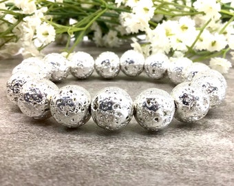 May include: A silver lava rock bracelet with round beads. The beads have a textured surface.