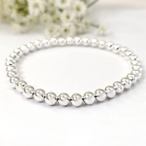 May include: A silver beaded bracelet with a simple design. The bracelet is made of small, round beads that are strung together on a thin wire. The bracelet is a classic and elegant piece of jewelry that can be worn on any occasion.
