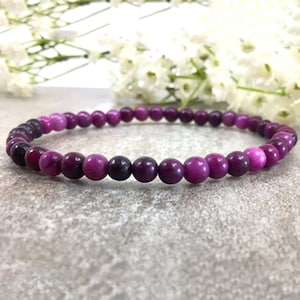 May include: A purple gemstone bracelet with graduated beads, ranging from light pink to dark purple.
