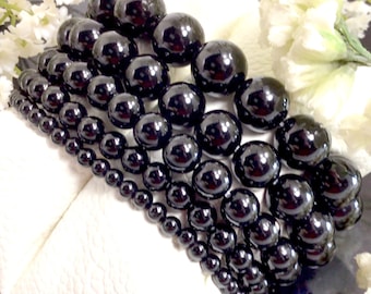 May include: A set of five black onyx beaded bracelets, each with a different size bead. The bracelets are stacked on top of each other, creating a layered look.