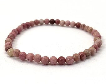 May include: A pink and white gemstone bracelet with round beads. The bracelet is made of natural stones and is approximately 7 inches in length.