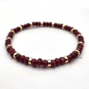 May include: A red gemstone bracelet with gold beads. The bracelet is made of small, faceted red gemstones and gold beads.