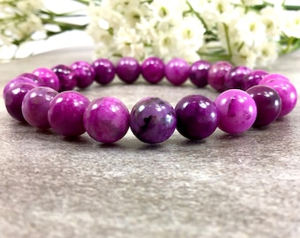 May include: A purple gemstone bracelet with round beads. The bracelet is made of natural stones and has a polished finish.