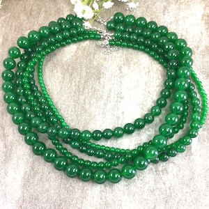May include: A necklace made of multiple strands of green jade beads. The beads are round and smooth, and they are strung on a silver chain.