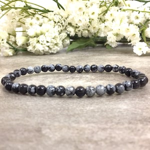 May include: A black and grey gemstone bracelet with small round beads.
