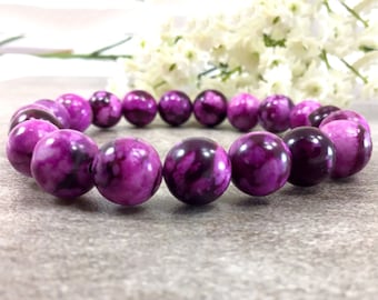 May include: A purple and white gemstone bracelet with round beads. The bracelet is made of natural stone and has a unique marbled pattern.