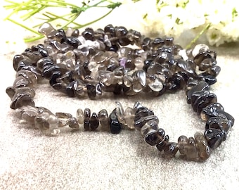 May include: A strand of dark brown smoky quartz chip beads. The beads are irregular in shape and have a translucent appearance.