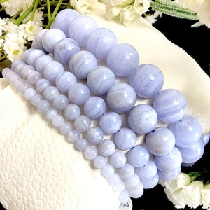 May include: A set of six blue lace agate beaded bracelets, each with a different size bead. The bracelets are stacked on top of each other, showing the different sizes and patterns of the beads.