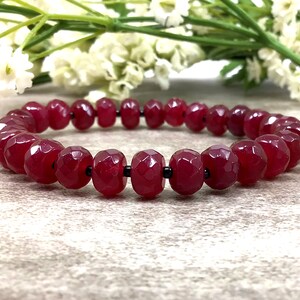 May include: A red gemstone bracelet with faceted beads and black spacers. The bracelet is made of natural stones and is approximately 7 inches in length.