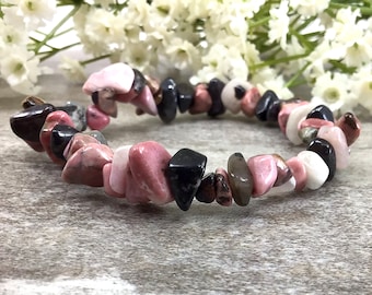 May include: A pink and black gemstone bracelet with irregular shaped beads. The bracelet is made with natural stones and is approximately 7 inches in length.