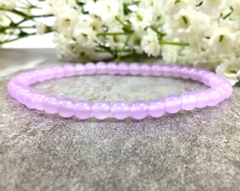 May include: A delicate bracelet made of light purple beads. The bracelet is made of small, round beads that are strung together on a thin elastic cord.