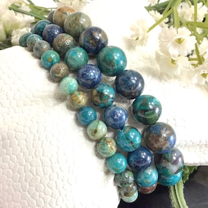 May include: Three turquoise, blue, and brown gemstone bracelets with round beads. The bracelets are stacked on top of each other.