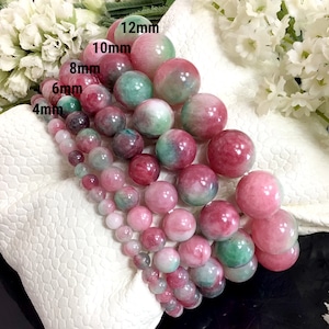 May include: A set of six strands of pink and green jade beads, each strand with a different size of beads, ranging from 4mm to 12mm. The beads are round and have a smooth, polished finish.