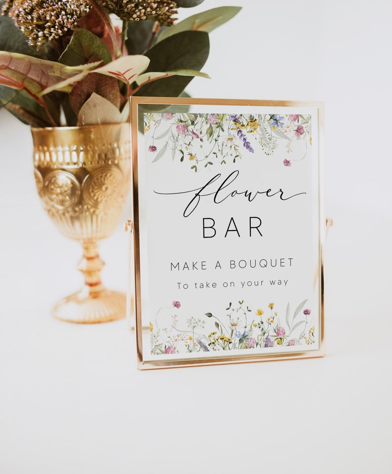 Pu&ograve; includere: Un cartello con cornice dorata con le parole "flower BAR" e "MAKE A BOUQUET To take on your way." Il cartello &egrave; decorato con illustrazioni floreali. Un calice dorato con fiori &egrave; sullo sfondo.