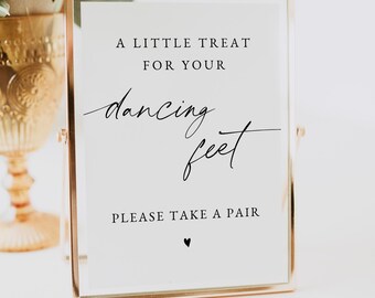 Op de afbeelding: Een ingelijst bord met gouden rand en witte achtergrond. Op het bord staat in zwart schrift "A LITTLE TREAT FOR YOUR dancing feet PLEASE TAKE A PAIR". Onderaan staat een klein zwart hartje. Geschikt voor een bruiloft of evenement.