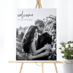 May include: Black and white wedding welcome sign with a photo of a couple embracing. The sign reads "welcome to our wedding" and "Kristine & Matthew 8.1.2020 Los Angeles, California".
