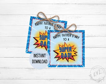 May include: Two Father's Day gift tags with a superhero theme. Each tag features the text "Happy Father's Day to a Super Dad!" in a comic book style, with a blue and red border and a burst graphic. Tied with twine.