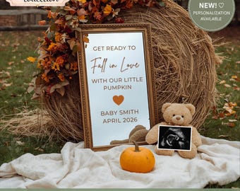 May include: A rectangular mirror in a gold frame featuring the text GET READY TO Fall in Love WITH OUR LITTLE PUMPKIN, a heart icon, BABY SMITH, and APRIL 2026. A small orange pumpkin and a light brown teddy bear holding a sonogram sit in front.