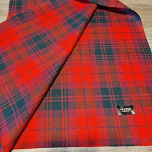 May include: A folded red and green plaid scarf. The scarf features a classic tartan pattern with a vibrant red base, accented by green and purple lines. The label in the corner reads "Art et Mode Creations".