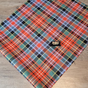 May include: A red, blue, green and black tartan fabric with a small gold tag that reads "Art & Made Creations".