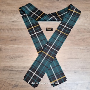 Peut inclure: Une écharpe à carreaux verts, noirs, blancs et jaunes avec des bords effilochés. L'écharpe est disposée en forme de X sur une surface en bois. Le texte "Art et Mode Creations" est visible sur l'écharpe.