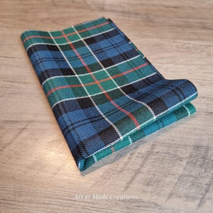 May include: Folded plaid pocket square in shades of blue, green, black, red, and white. The fabric features a classic tartan pattern. The pocket square is folded neatly, showcasing the intricate design.