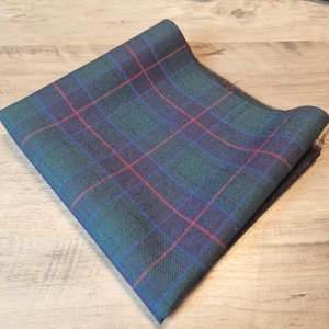 May include: A folded piece of green, blue, and red plaid fabric. The fabric has a woven texture.