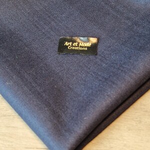 May include: A dark blue fabric swatch with a black label that reads "Art et Mode Creations".