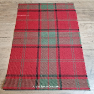 May include: A rectangular piece of red plaid fabric with black, green, and brown lines. The fabric has a rough texture and the words "Art et Mode Creations" are printed at the bottom.