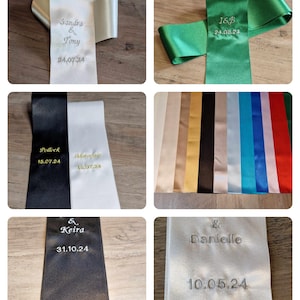 May include: A collection of smooth satin ribbons in various colors including white, green, black, and gold. Each ribbon features custom embroidery with names and dates such as Sandra & Tony 24.07.24, I&B 24.08.24, Pollock 15.07.24, & Keira 31.10.24, and Danielle 10.05.24.