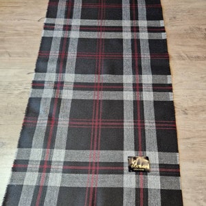 May include: A black, white, and red plaid fabric with a small black label that says "Thistle & Thistle Creations".