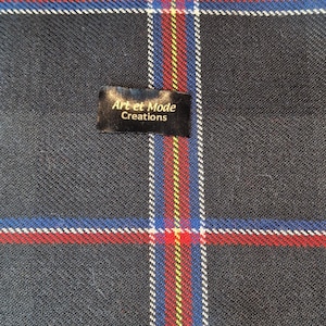 May include: A black and white plaid fabric with red, yellow, and blue stripes. The fabric has a label that says "Art et Mode Creations".