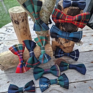 Peut inclure: Plusieurs nœuds papillon en tartan de différentes couleurs, notamment rouge, vert et bleu. Ils sont présentés sur une surface en bois et des branches. Le texte "Art et Mode Creations" est visible.