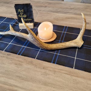 May include: A blue and white plaid table runner with a white candle and a set of antlers on top. The text "Art et Mode Creations" is visible in the upper right corner of the image.