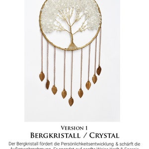 May include: A gold-toned metal dreamcatcher with a clear crystal tree design and gold leaf accents. The text "VERSION 1 BERGKRISTALL / CRYSTAL" is below the dreamcatcher. The text below reads "Der Bergkristall f&ouml;rdert die Pers&ouml;nlichkeitsentwicklung & sch&auml;rft die Au&szlig;enwahrnehmung. Er spendet auf sanfte Weise Kraft & Energie Rock crystal promotes personality development and sharpens external perception. It gently gives strength and energy"