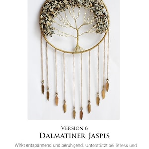 May include: A gold wire tree of life with white and black Dalmatian Jasper stones. The tree is hanging from a gold hoop with a chain of gold feathers.