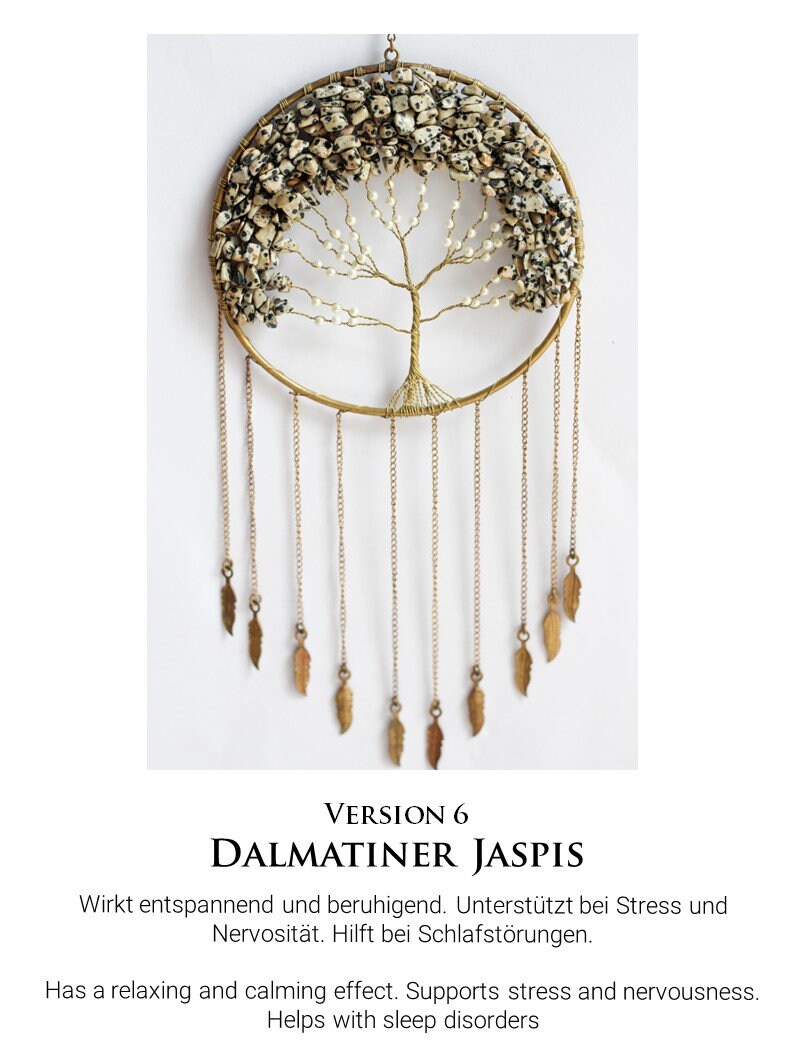 May include: A gold wire tree of life with white and black Dalmatian Jasper stones. The tree is hanging from a gold hoop with a chain of gold feathers.