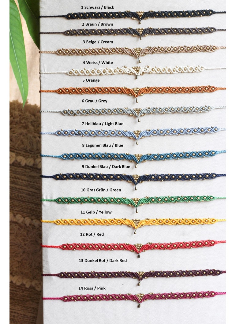 May include: A set of 14 colorful friendship bracelets with gold beads and a gold pendant. The bracelets are arranged in a vertical row, with the colors ranging from black to pink.